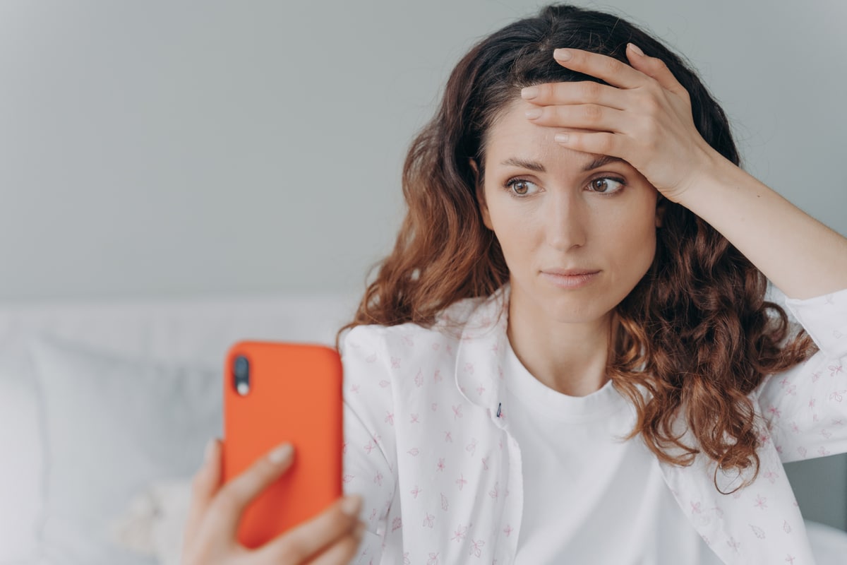 une fille inquiète lit des informations sur les problèmes en regardant l'écran du smartphone. crise de stress et d'anxiété.