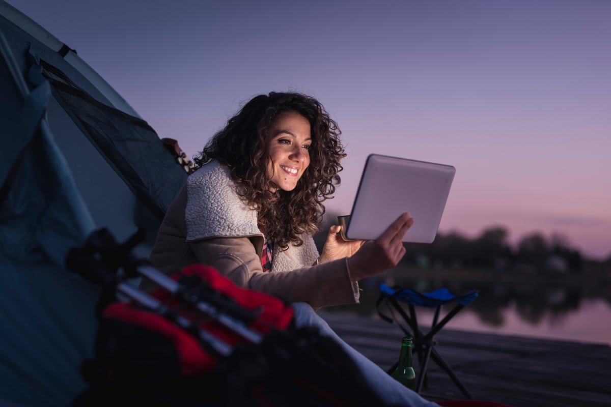 femme fait du camping la nuit et regarde sa tablette. équipement gadgets pour camping, randonnée, loisirs nature, aventures
