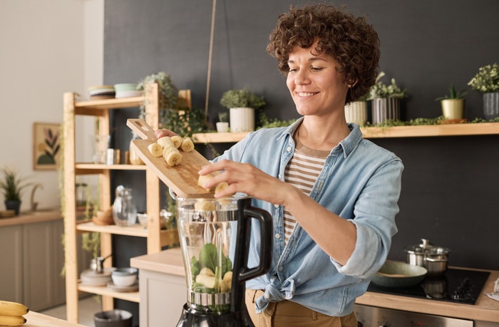  Femme ajoutant des fruits dans un smoothie mixer machine