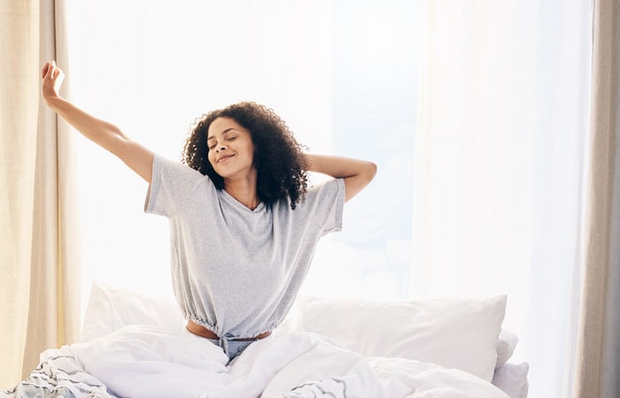 Femme noire s'étirant le matin et se réveillant en pleine forme