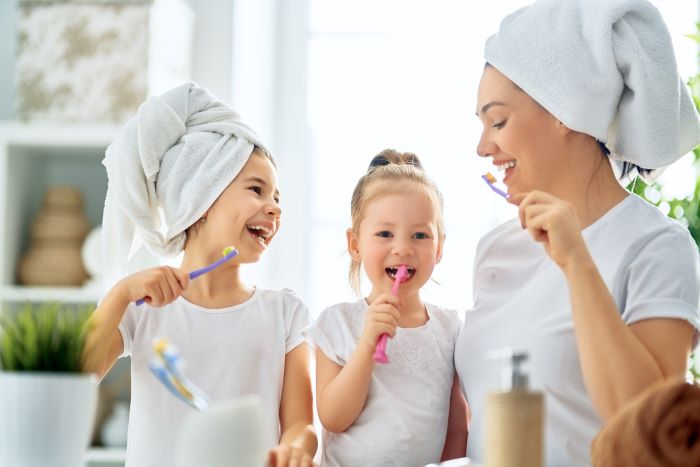 Femme et enfants qui se brossent les dents pour une bonne hygiene bucco dentaire 