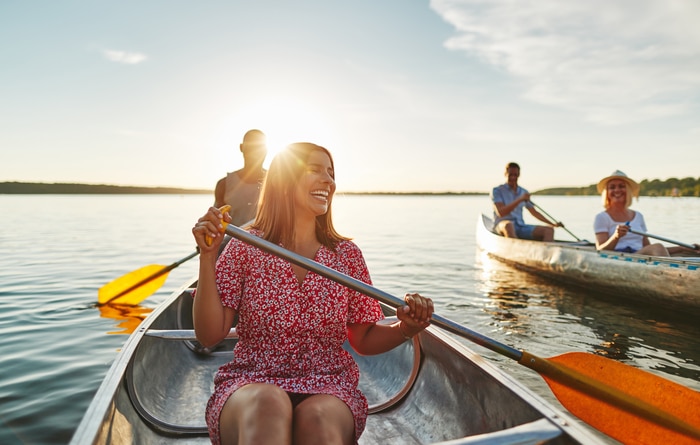 Femme qui rit faisant du canoë avec des amis en fin de compte 2024