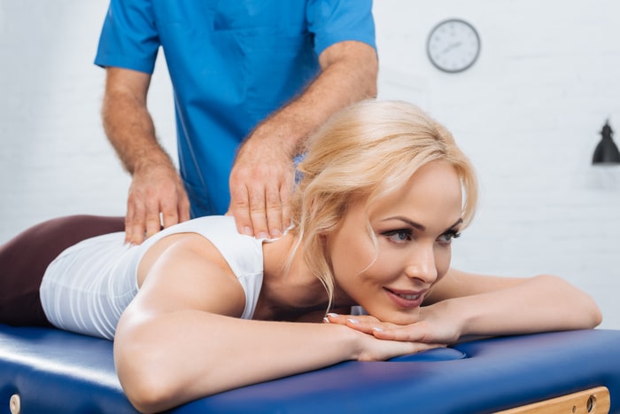 Vue partielle du massothérapeute effectuant un massage du dos sur une femme 