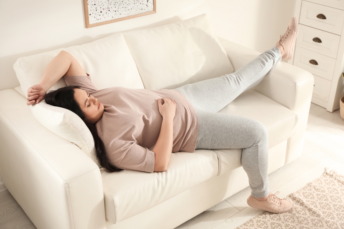 femme forte allongé sur canapé représentant la relation entre le sommeil, l'insomnie et la prise de poids
