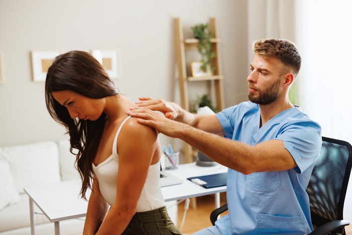 Une jeune femme souffrant de douleurs au cou est examinée par un chiropracteur