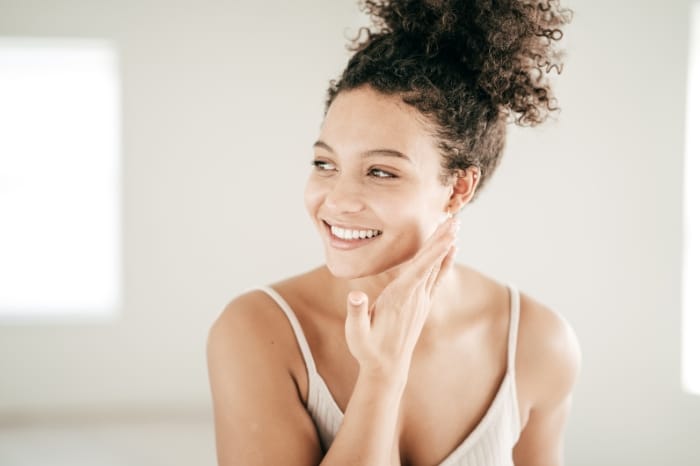 belle jeune femme aux cheveux bouclés ayant pris soin de sa peau, rituel bien-être beauté