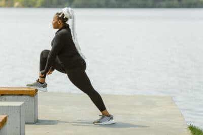 femme de type africain fait du yoga en plein air au bord de la plage avec un legging grande taille confortable