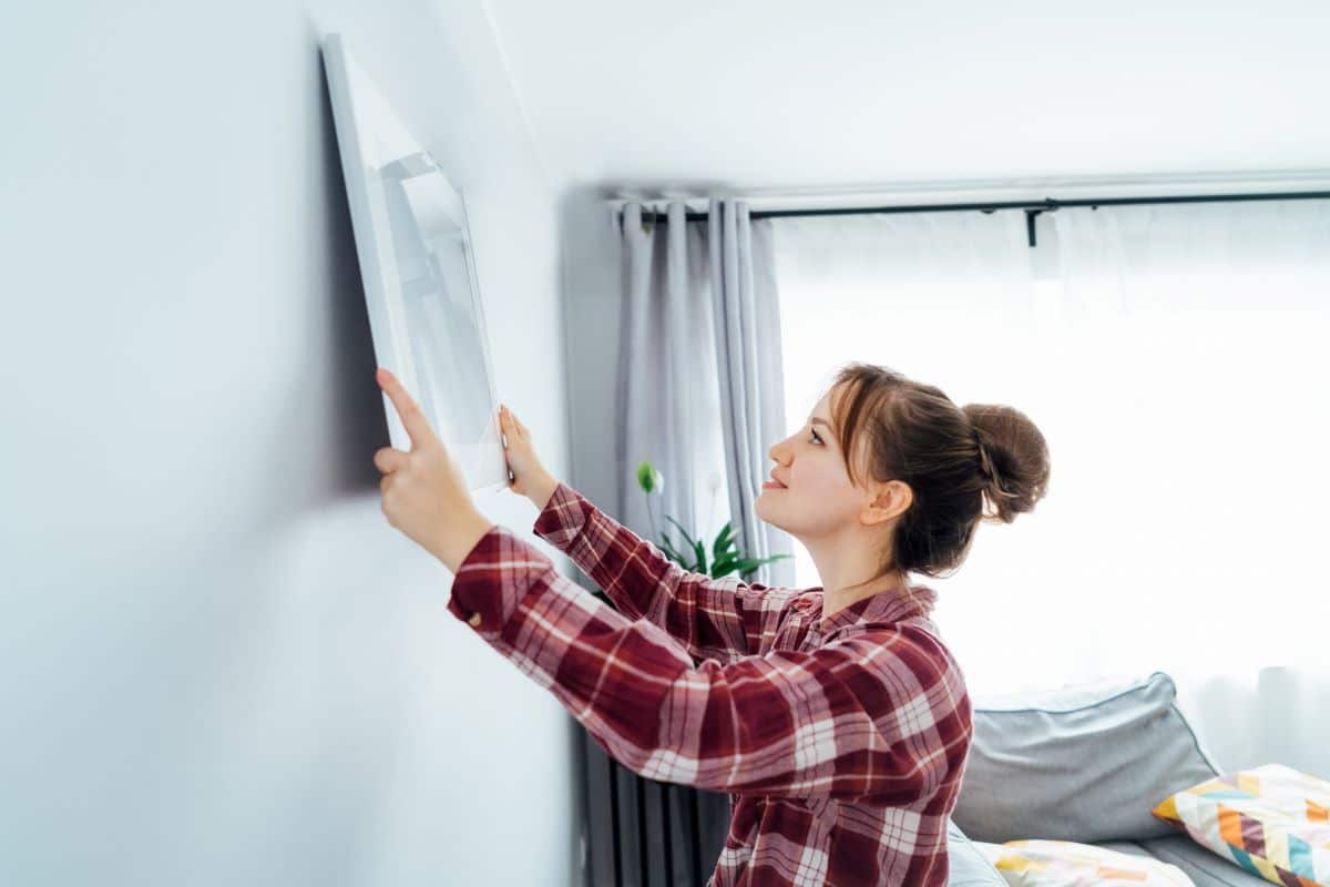 Femme qui pose un tableau de street art pour la decoration interieur