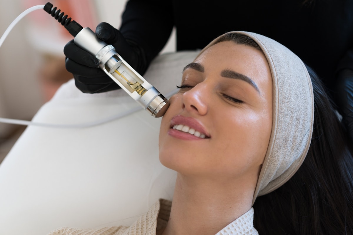 belle femme brune en train de faire un soin hydrofacial, vue de profil