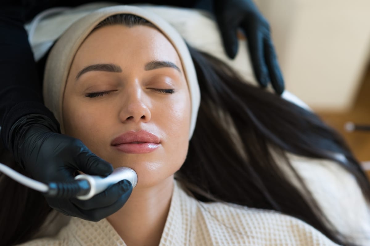 belle femme brune en train de faire un soin hydrafacial, vue de profil