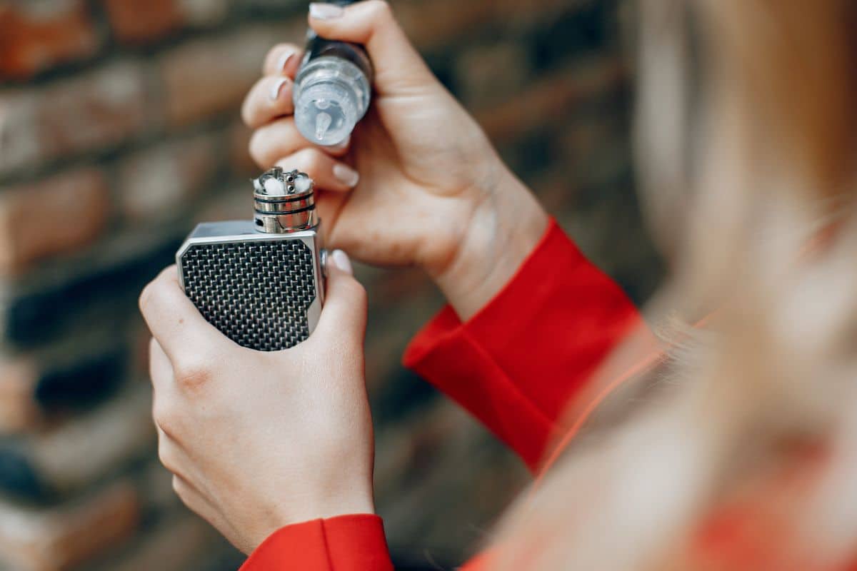 femme qui met du liquide pour vapoter dans cigarette électronique vapoteuse