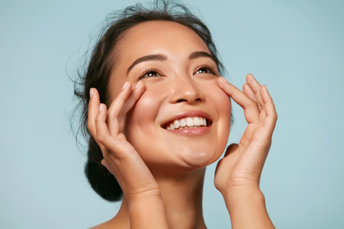 belle femme asiatique arbore un large sourire avec une peau rayonnante éclatante