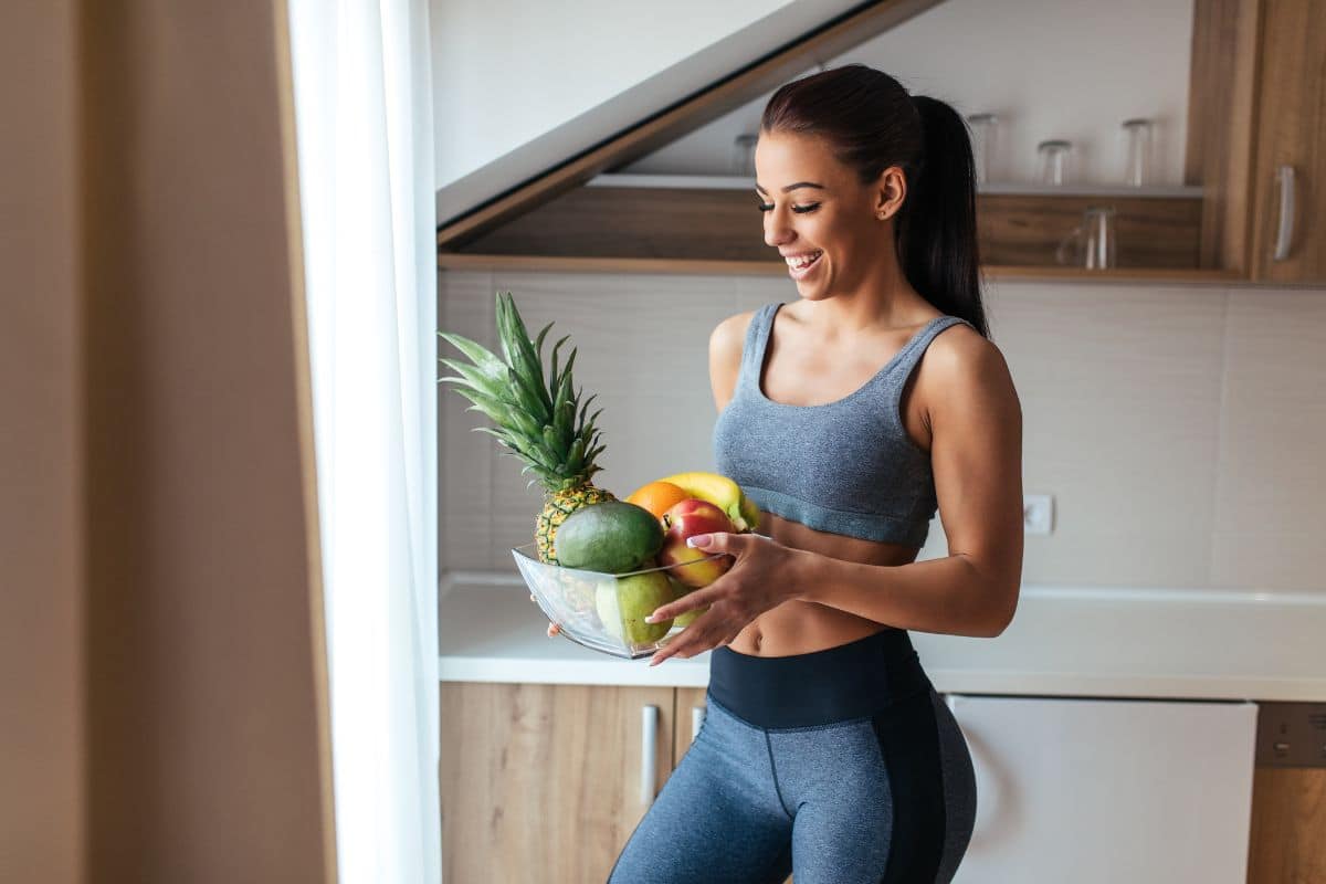 belle femme brune sportive qui tient un panier de fruit, concept d'une vie saine