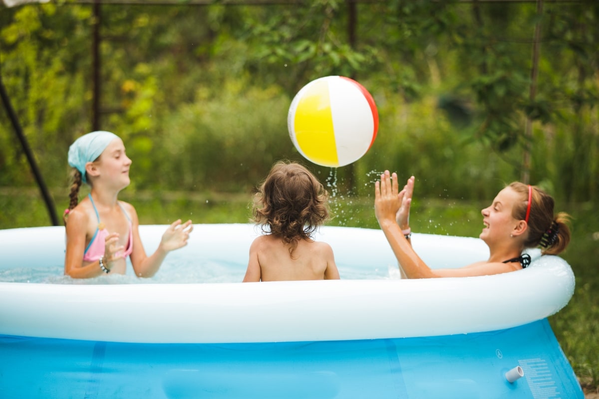 enfants jouants avec un ballon dans une piscine gonflable