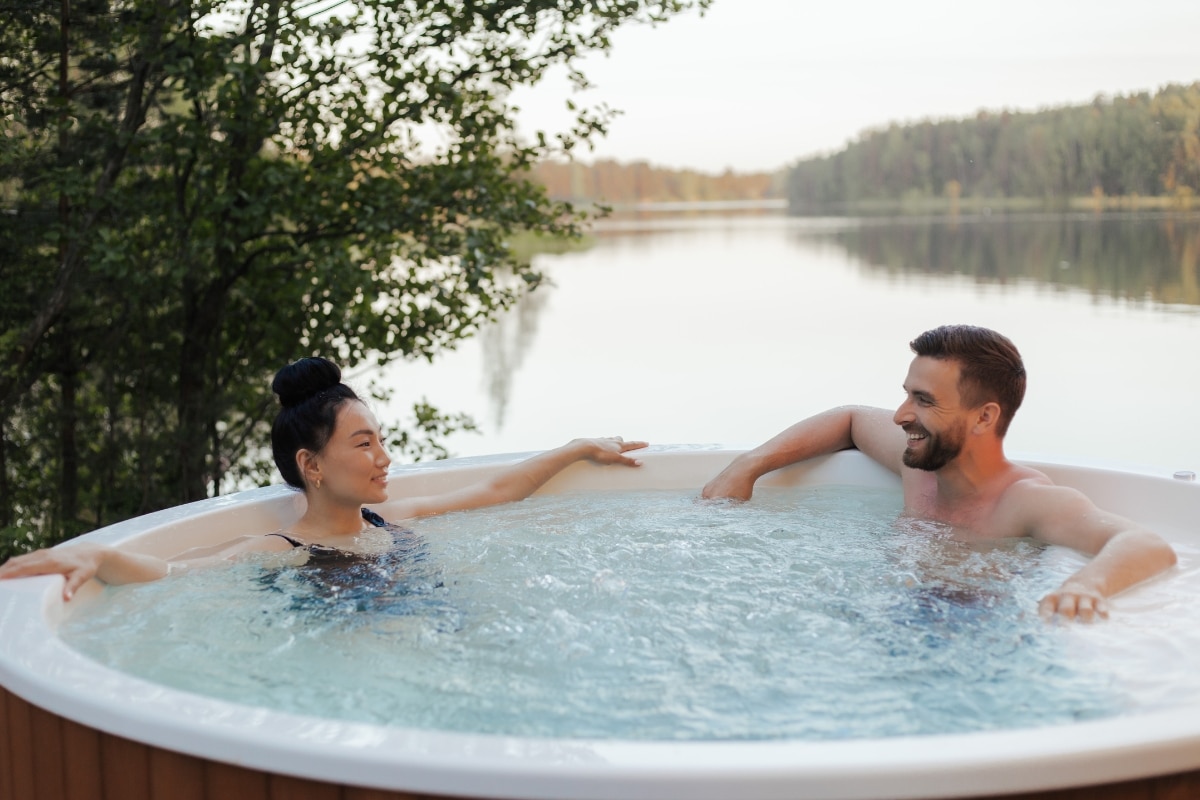 un homme et une femme discutent dans une piscine gonflable au bord d'un lac en pleine nature