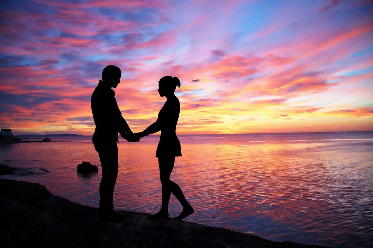 couple au bord de la plage avec couchée de soleil romantique