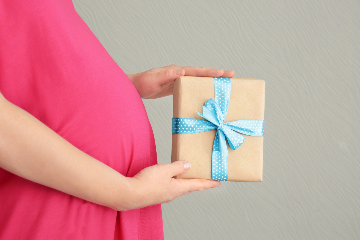 Le ventre d'une femme enceinte recevant un cadeau pour sa grossesse