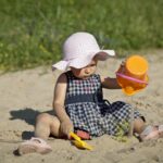 sandales d'eau bébé, une petite fille joue avec du sable sur la plage