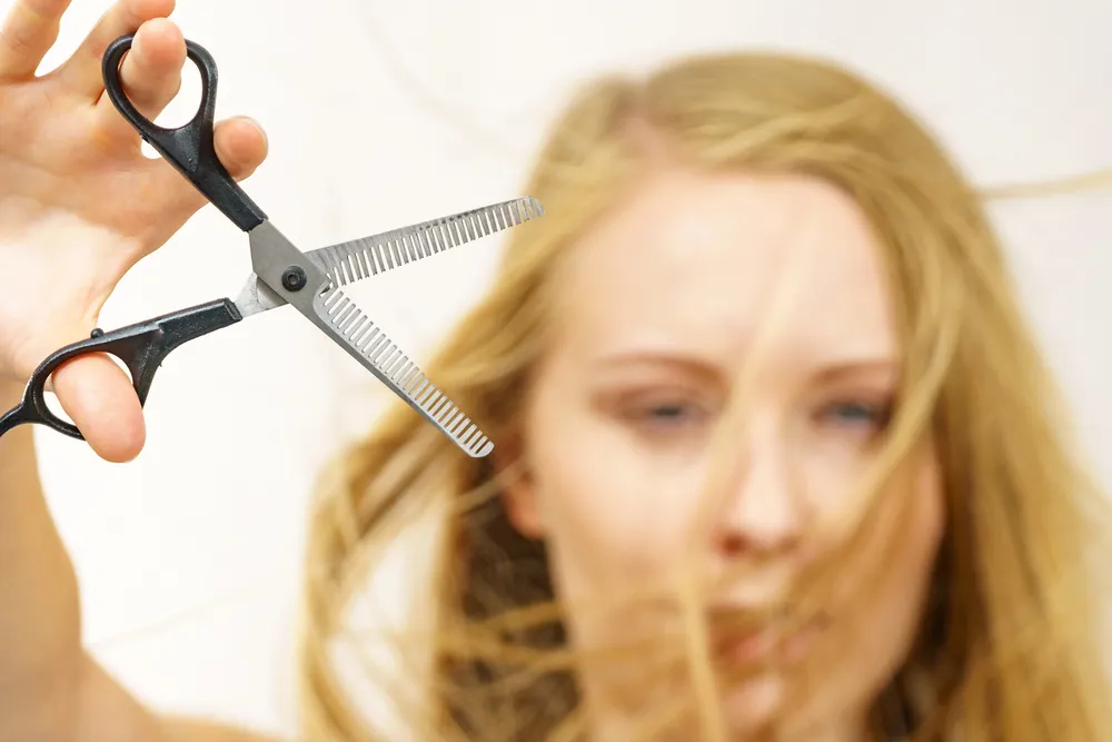 Femme préparant ses ciseaux désépaississant pour se couper les cheveux seule à la maison 
