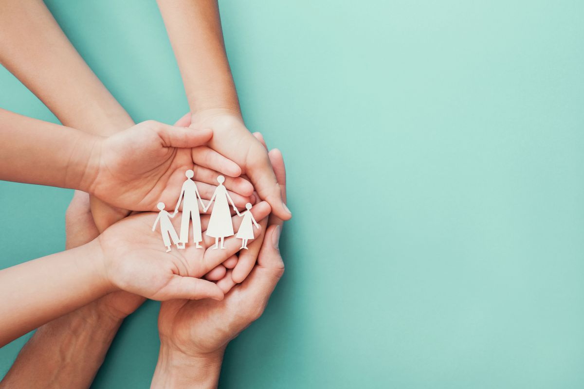 des mains empilés, papa, maman et enfants, tenant des figurines en carton représentant une famille, symbolisant la protection de la famille, la bonne santé, l'union familiale