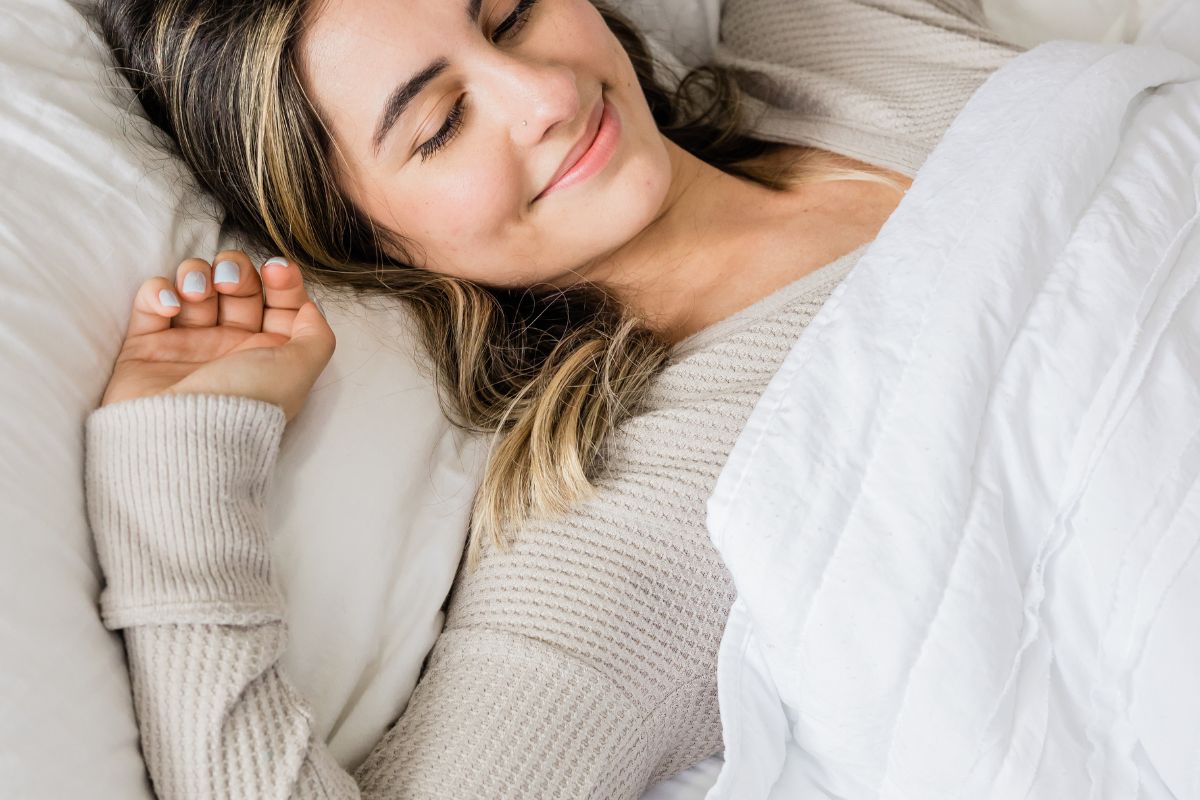 une femme qui se réveille et s'étire sur son lit apres avoir passé une très bonne nuit de sommeil
