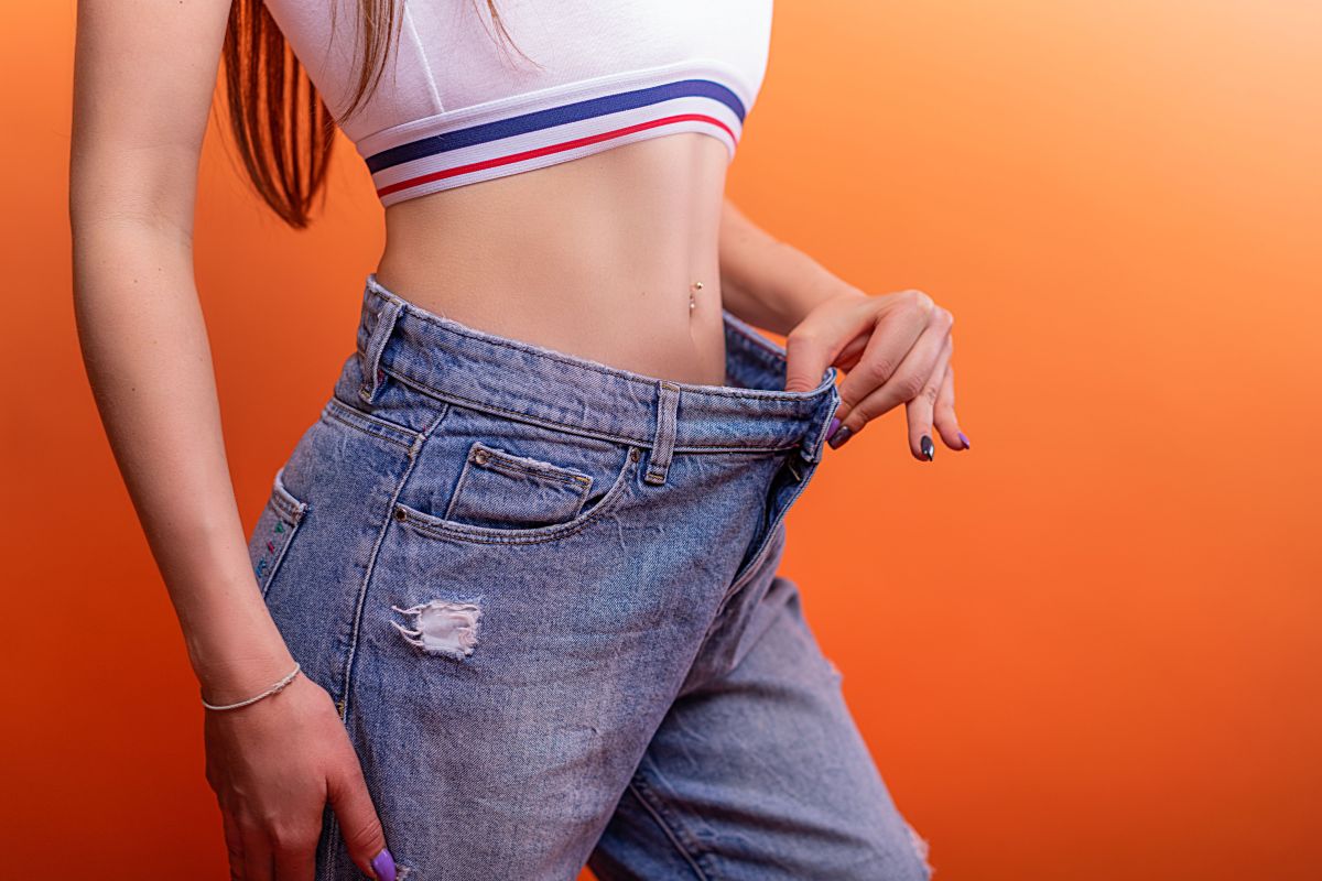 une femme a la belle silhouette dont le jean est devenu trop ample pour elle car elle a perdu du poids