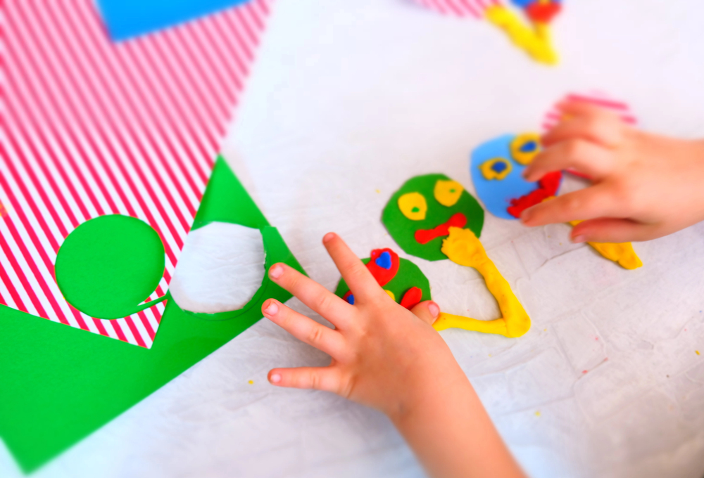 des mains d'enfants s'amusent avec de la pâte à modeler en dessinant des figures rigolotes