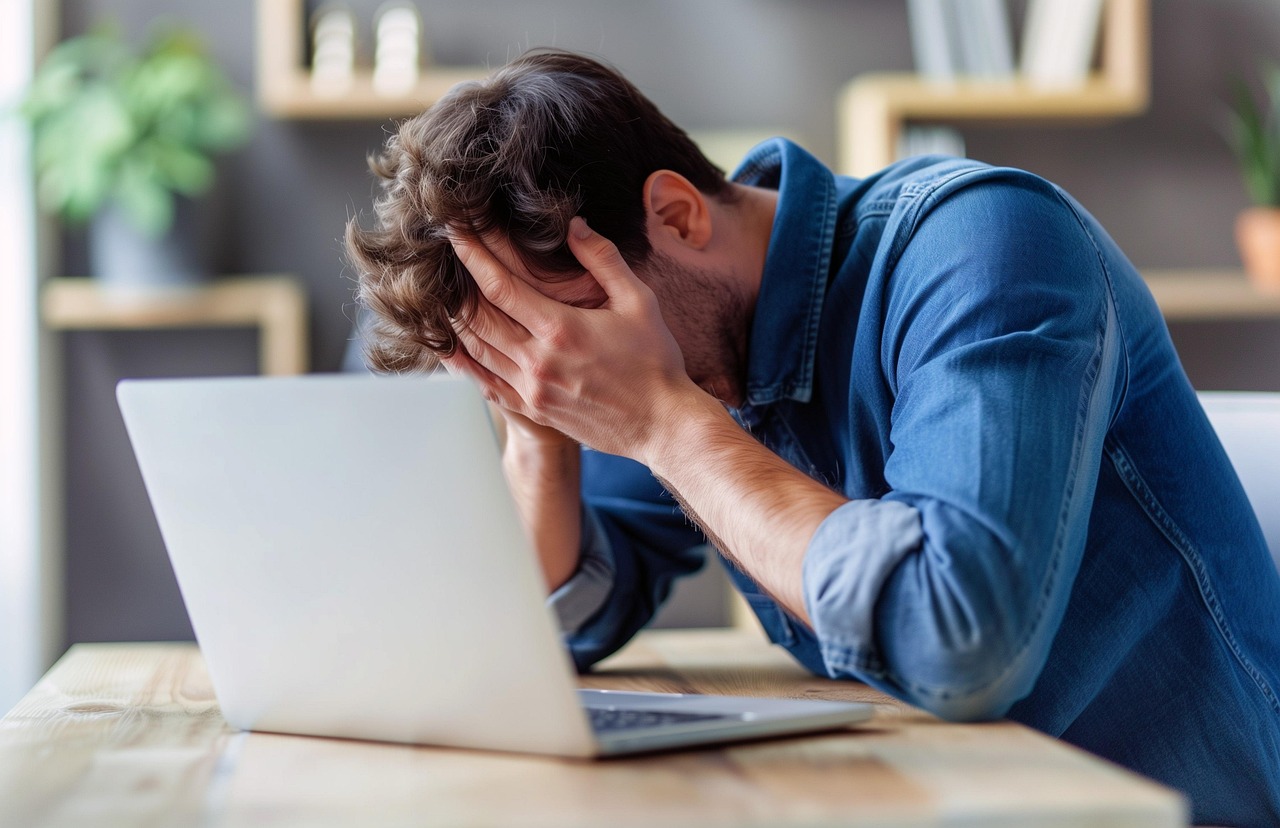 Un homme se prend la tete dans les mains a cause du manque de sommeil et la fatigue chronique