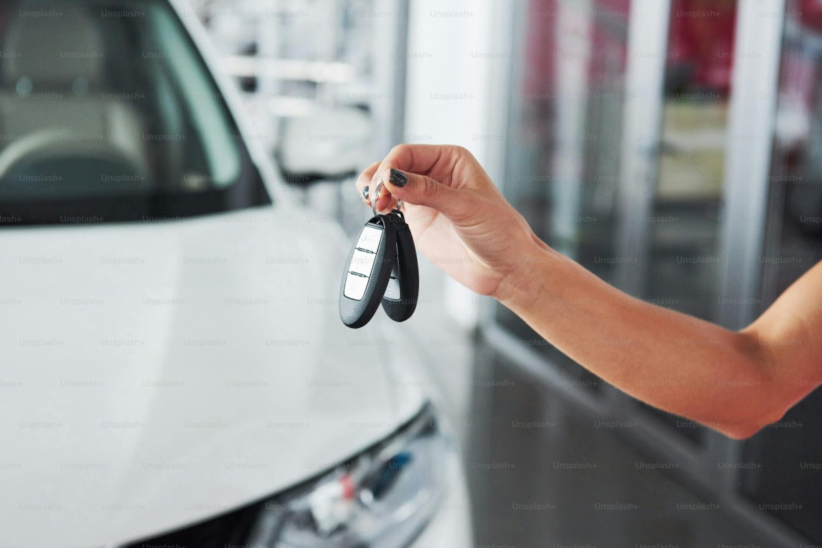 Une main de femme Tient des clés de sa voiture de location en arrière plan, dans une agence de location vacances