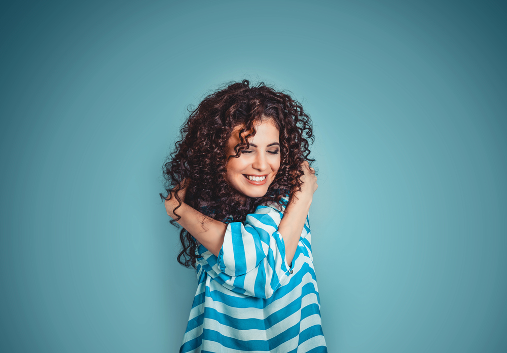 Portrait d’une femme souriante, symbole de confiance en soi et d’estime personnelle, se calinant elle meme