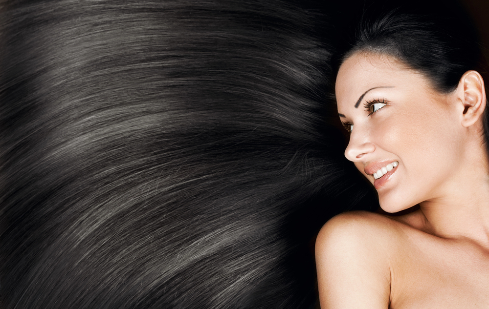 Femme aux cheveux noirs lisses et brillants, symbole de santé capillaire et d’éclat naturel