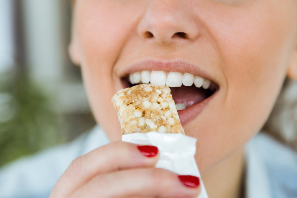 gros plan bouche femme croque une barre de céréales bio, Snack sans sucre raffiné