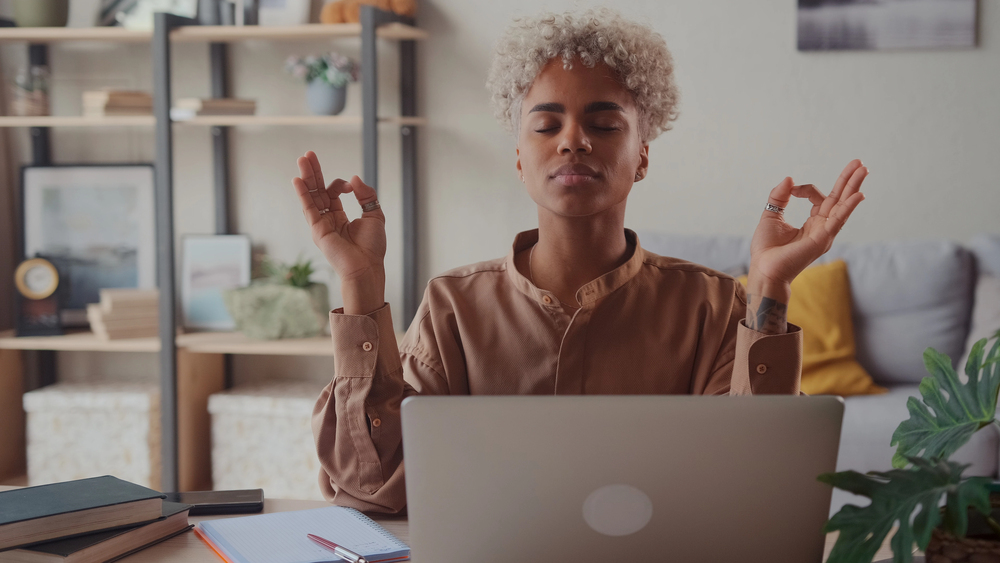Femme zen qui travaille à domicile avec un smoothie, posture de yoga, équilibre entre productivité et soin personnel