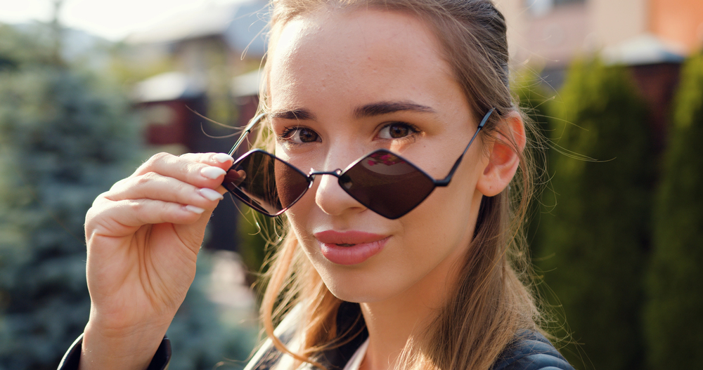 Femme blonde avec lunettes de soleil à monture géométrique, parfaites pour un visage ovale ou triangulaire