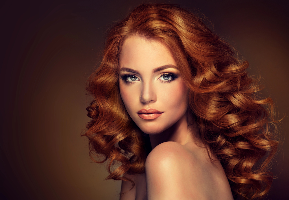Femme aux cheveux roux bouclés mise en lumière, coiffure glamour et volumineuse