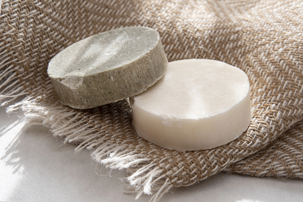 Deux shampoings solides posés sur une serviette beige, ambiance naturelle et douce