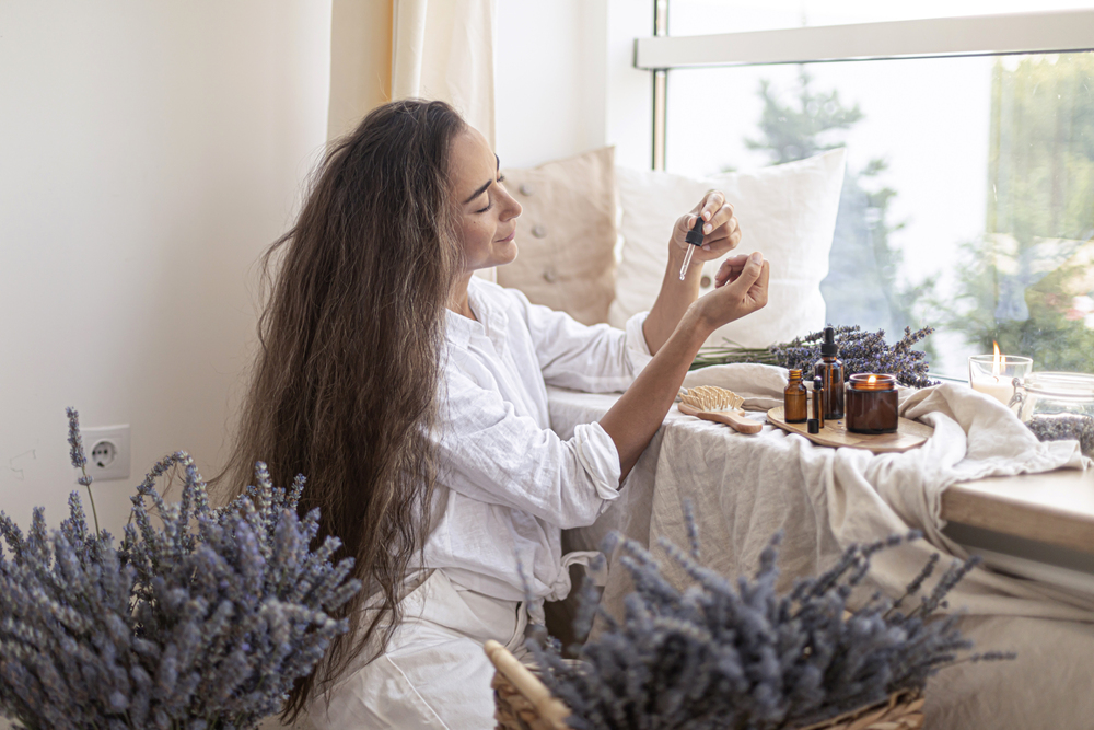 Femme en peignoir vaporisant une brume florale dans une ambiance spa apaisante avec lavande