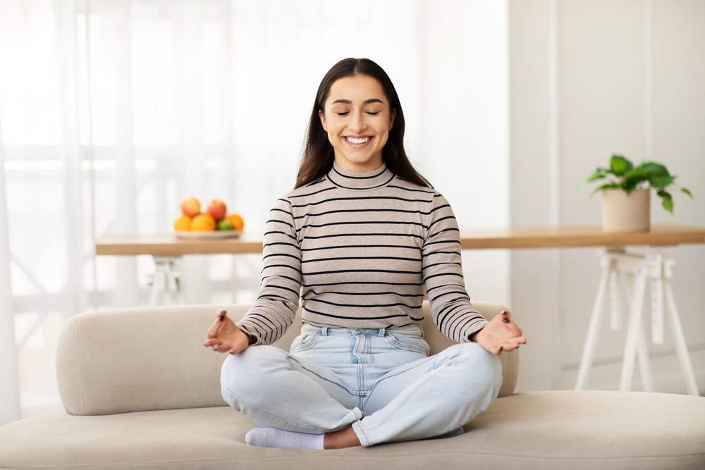 Femme en posture de méditation assise dans un intérieur lumineux et épuré