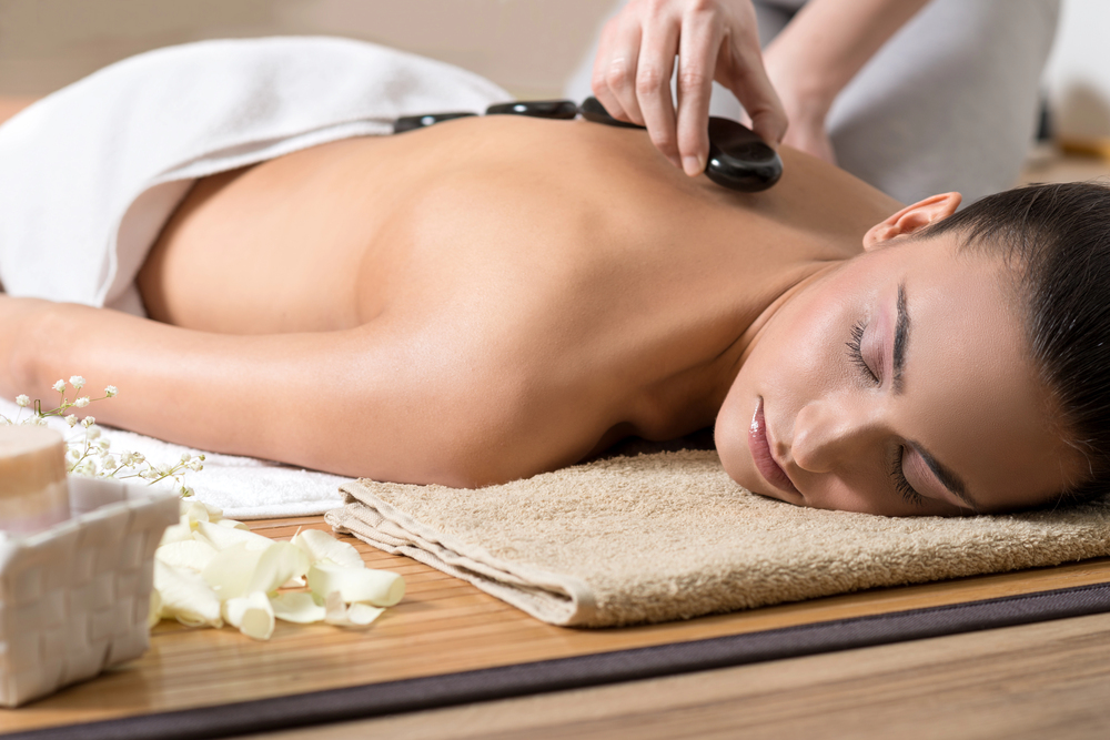 Femme recevant un massage aux pierres chaudes dans un spa bien-être, ambiance détente et chaleur