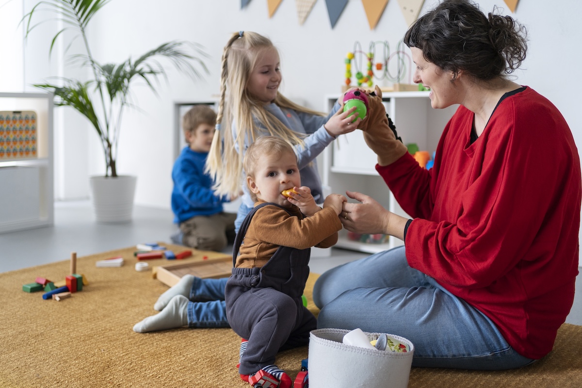 Assistante maternelle jouant avec des enfants dans un espace d’éveil coloré