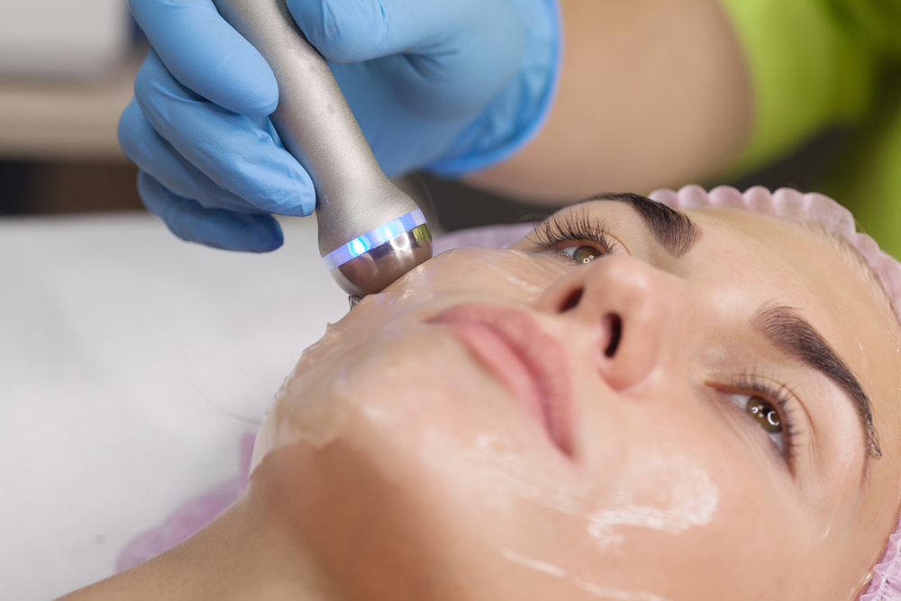 femme qui recoit un soin anti ride avec un appareil en institut, zoom sur visage et appareil