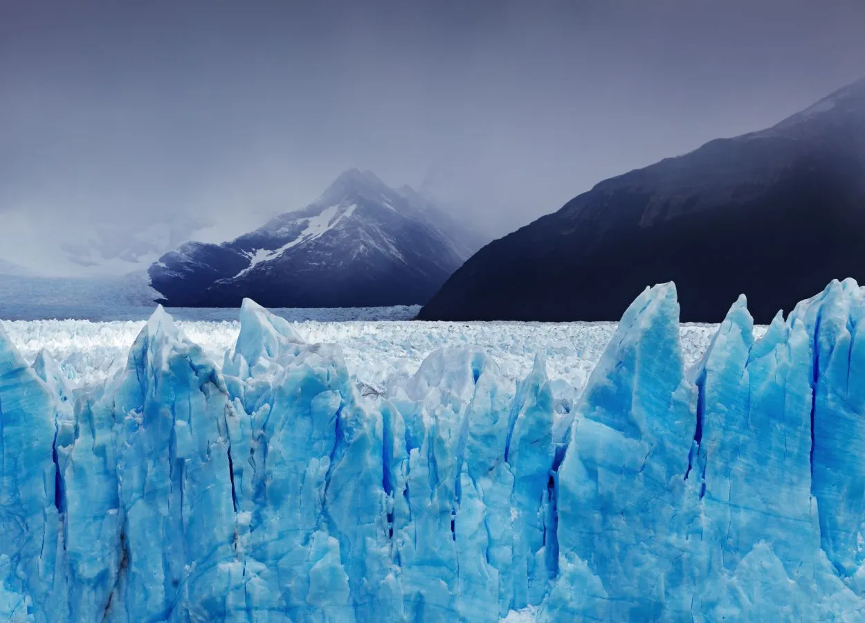 Vue panoramique du glacier Perito Moreno en Patagonie, blocs de glace bleutés sous un ciel dramatique