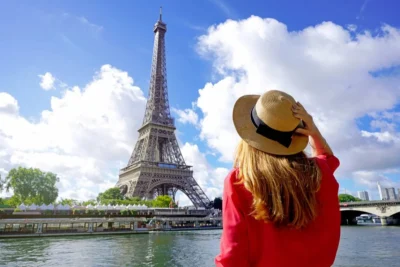 Jeune femme en chapeau contemplant la Tour Eiffel depuis la Seine par une journée ensoleillée
