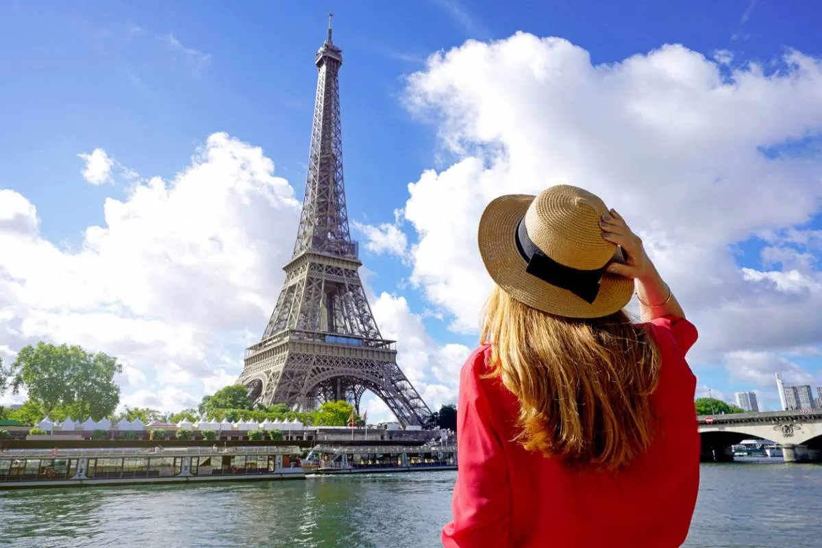 Jeune femme en chapeau contemplant la Tour Eiffel depuis la Seine par une journée ensoleillée