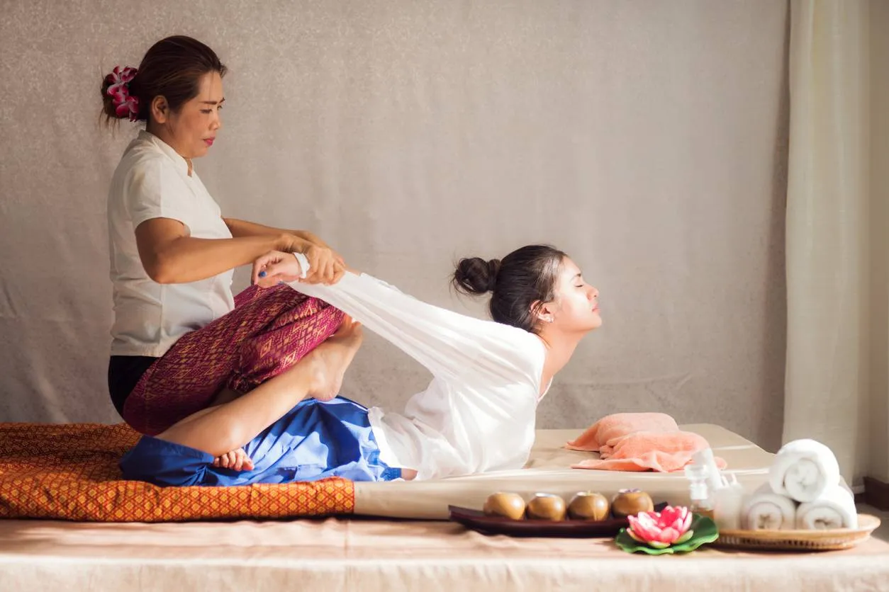 Praticienne effectuant un massage thaï traditionnel sur une femme allongée dans un spa