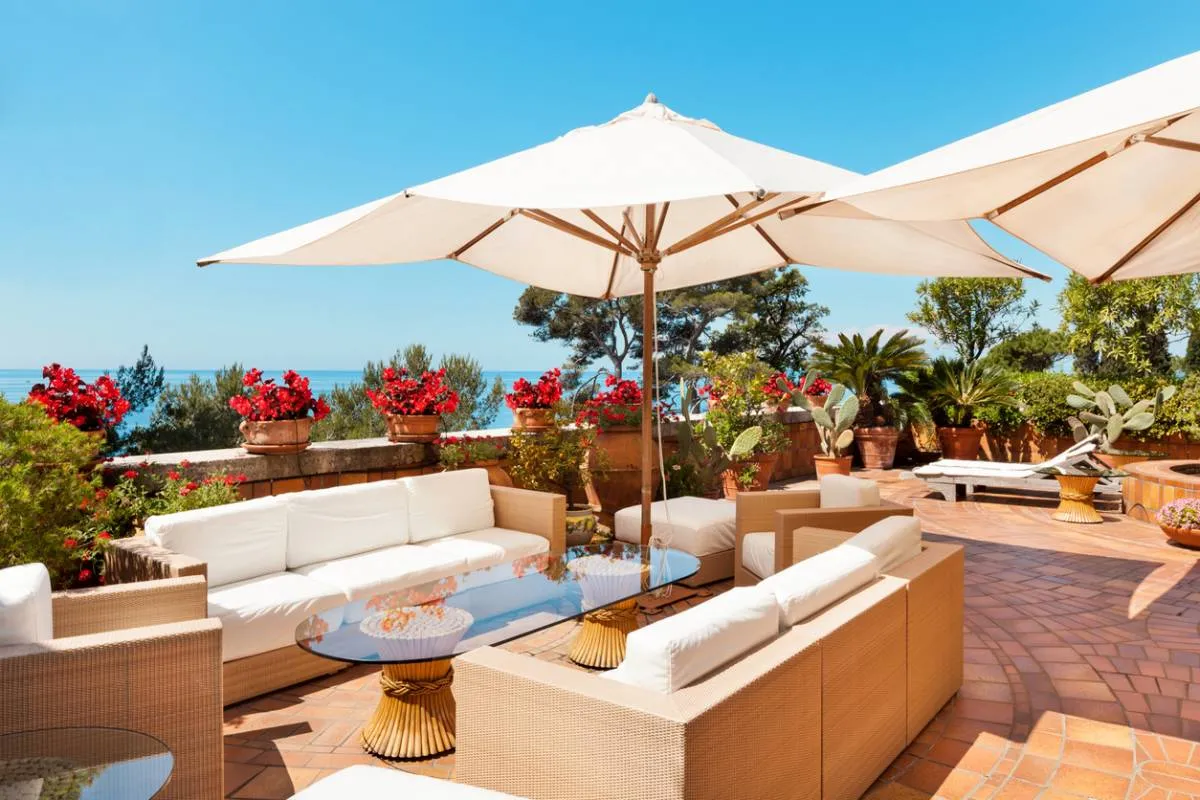 Terrasse méditerranéenne avec grand parasol blanc ombrageant un salon de jardin en rotin moderne