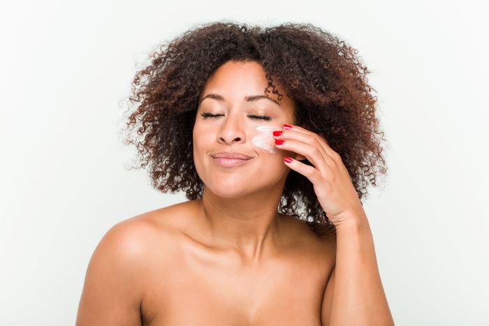 Une femme qui applique une creme pour peau noire 