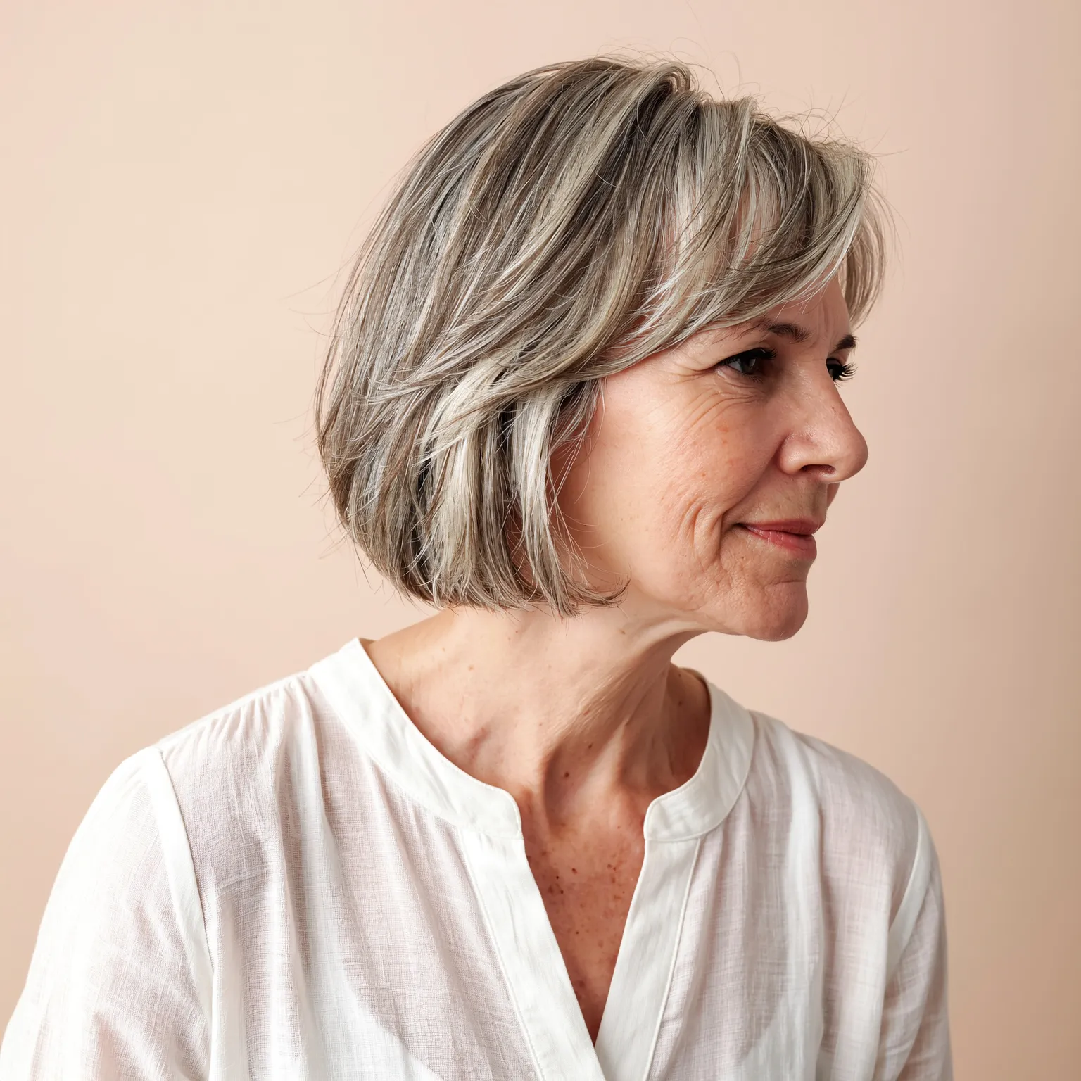 Carré doux superposé pour femme de 65 ans, coupe grise dégradée au volume léger et naturel, look chic et moderne.