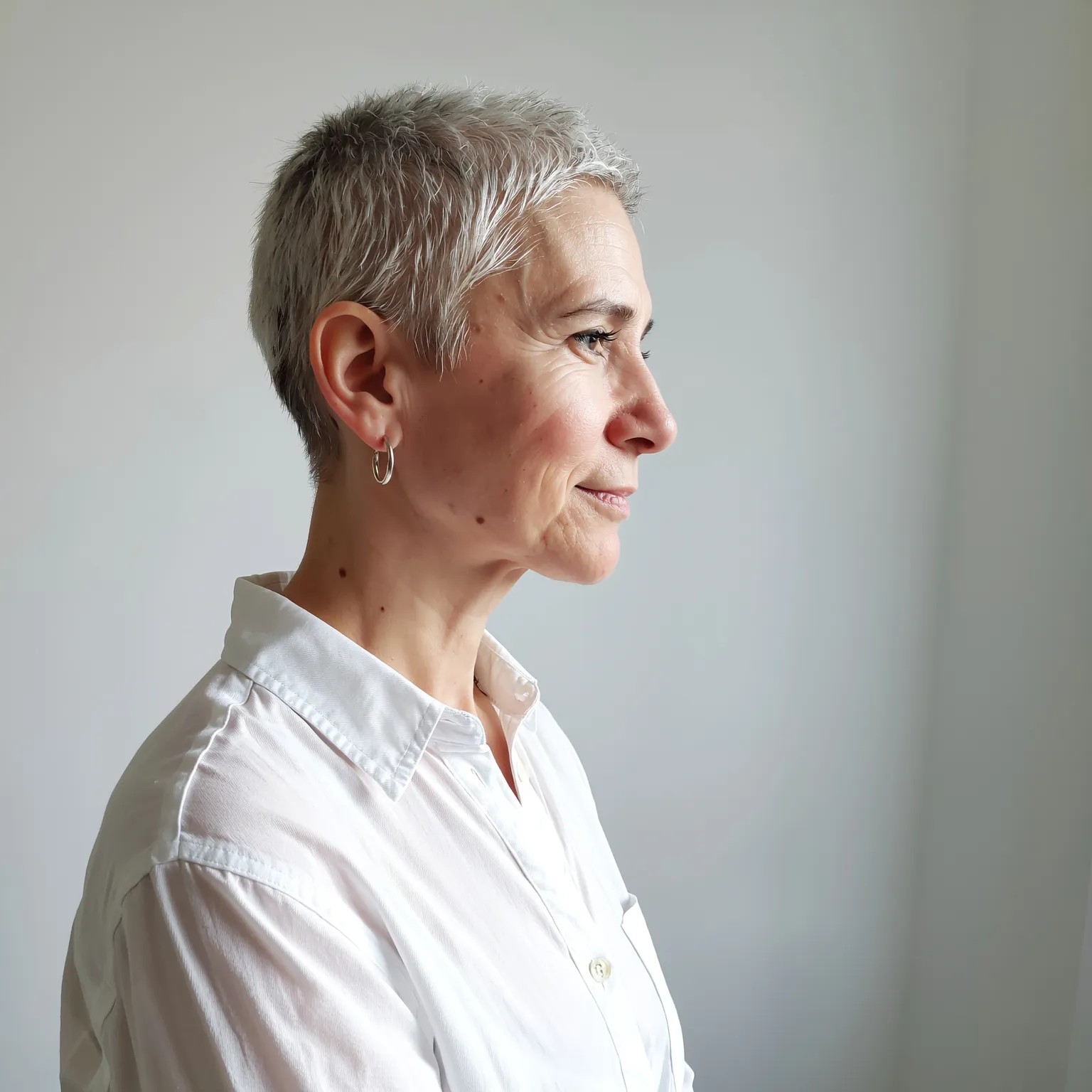 Coupe courte platine femme 59 ans, coiffure lisse et élégante en lumière de studio.