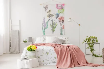 Lit coffre beige dans une chambre moderne lumineuse avec déco florale et couverture rose poudré, optimisant l’espace avec élégance.